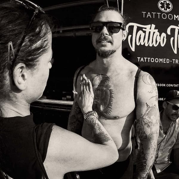 Getatoëerde man wordt ingesmeerd met After Tattoo